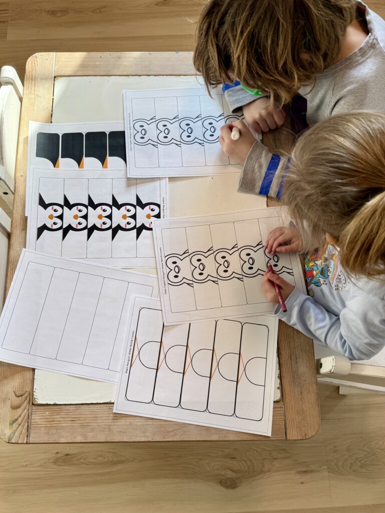 two children coloring water bottle labels that are penguins