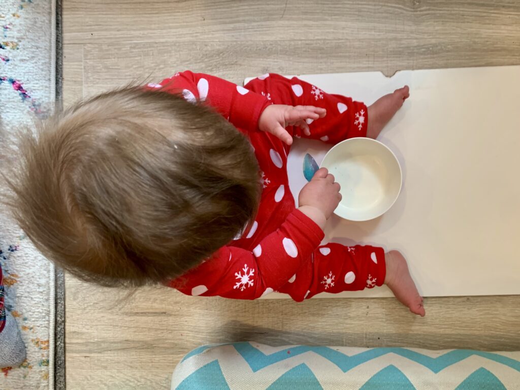 Small toddler holding an ice cube dyed blue and shaped like a fish