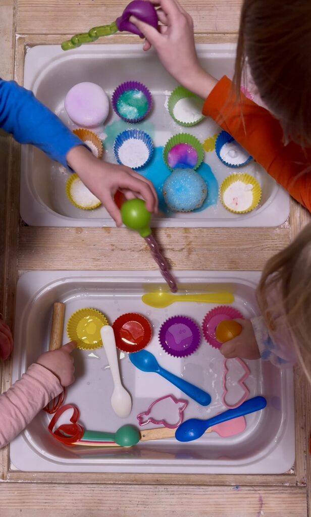 Children with droppers squirting vinegar onto baking soda, creating overflowing bubbles of all different colors.