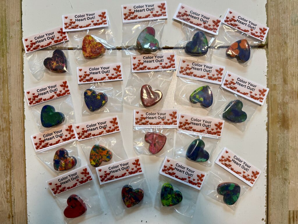 Heart Shaped Crayon Valentines - multi colored crayons melted into the shape of a heart in a clear plastic bag with a bag tag that reads "Color Your Heart Out"