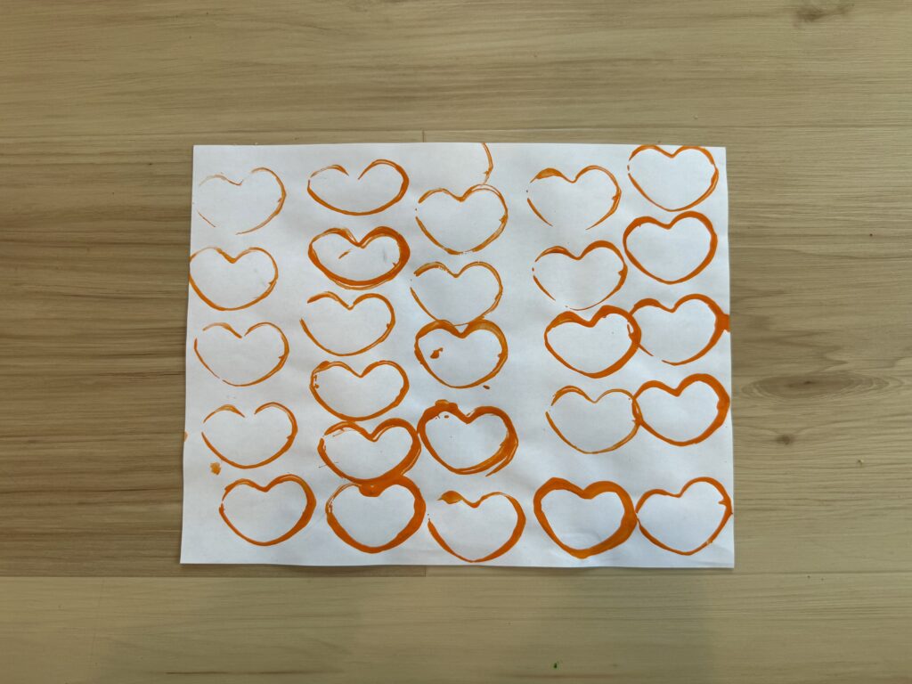 A photo of orange hearts painted on paper.