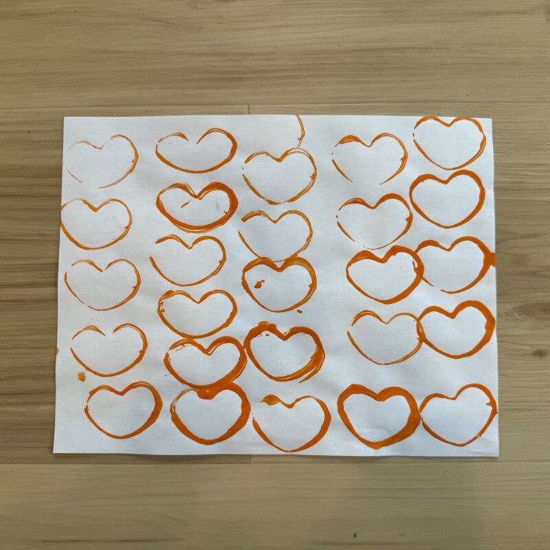 A photo of orange hearts painted on paper.