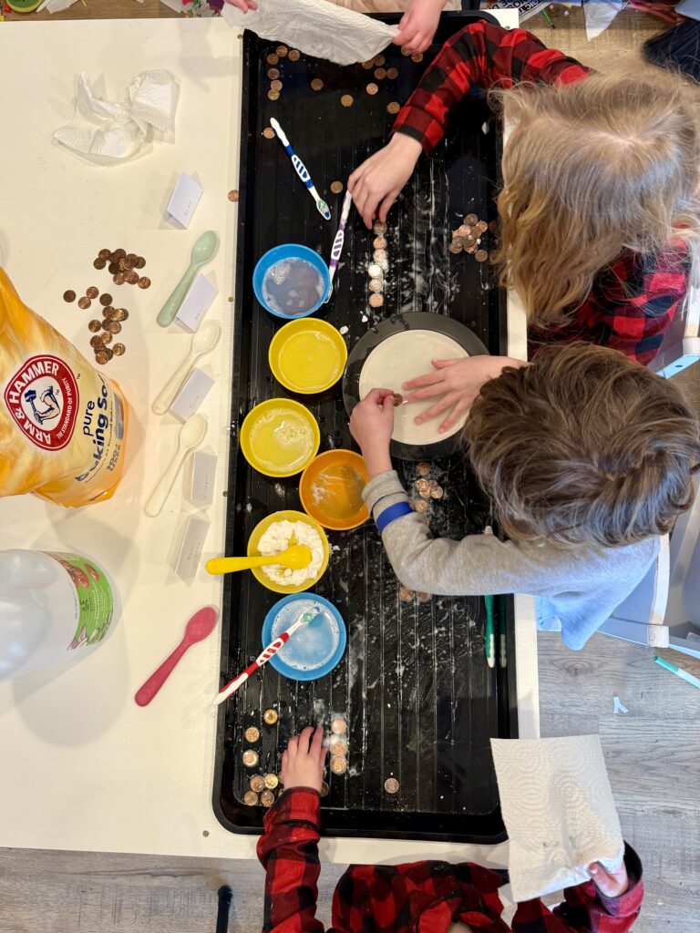 Photo of 4 kids cleaning pennies with toothbrushes, soap, water, baking soda, and vinegar