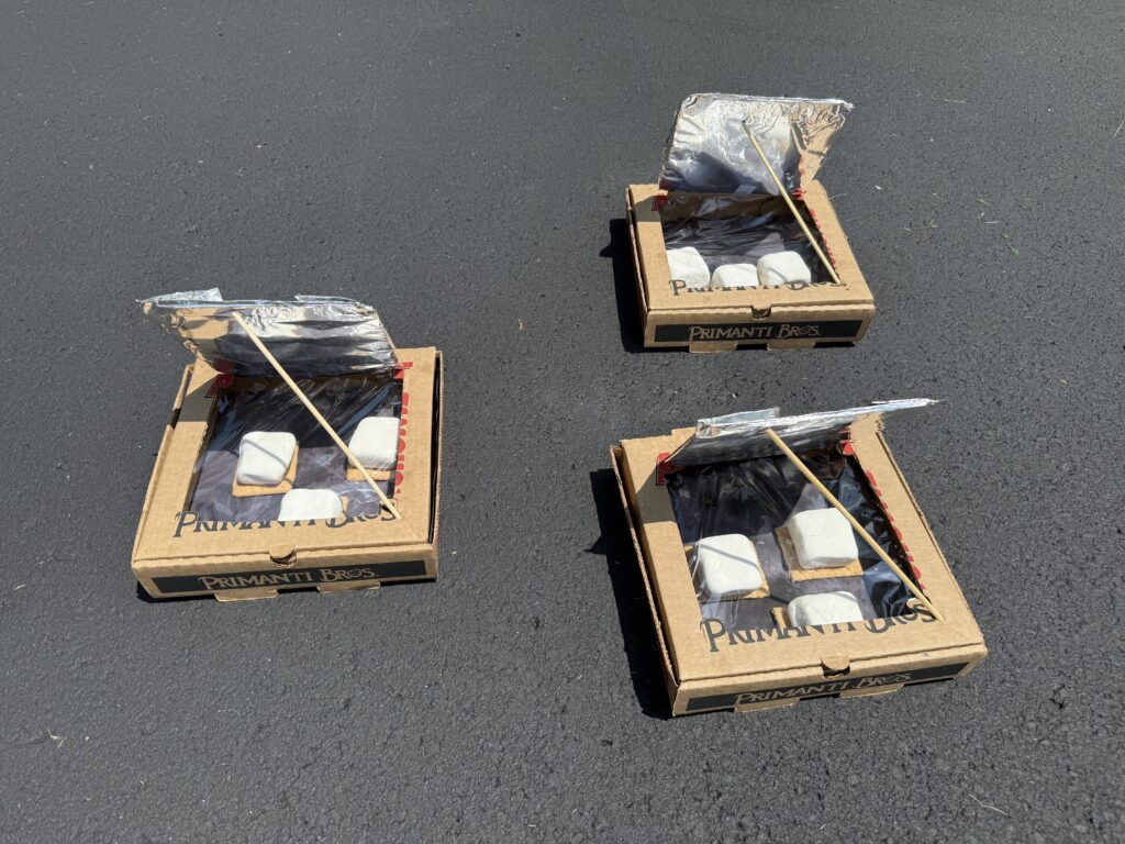 Solar S'mores Oven: pizza boxes with aluminum foil reflecting the sun into the box. Graham crackers with marshmallows on top baking in the sun.